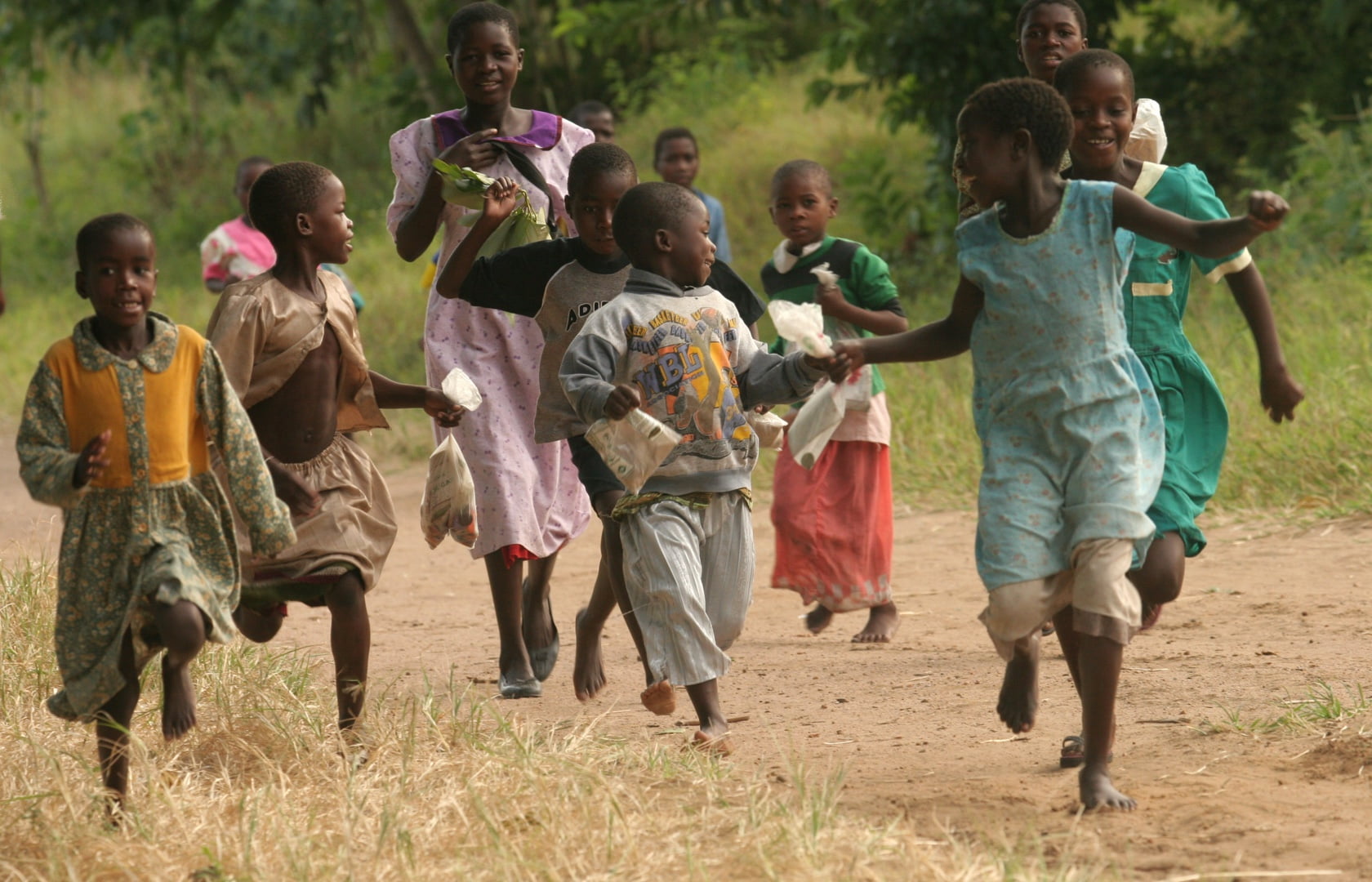 Children running barefoot on a dirt road